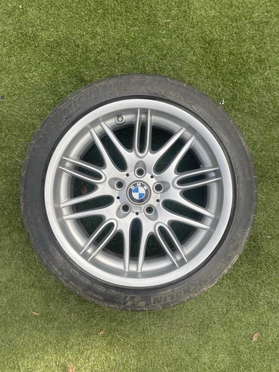 Silver BMW multi-spoke wheel with a mounted tire on grass