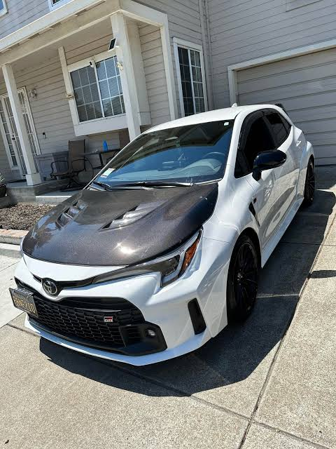 White Toyota with a dark vented hood installed